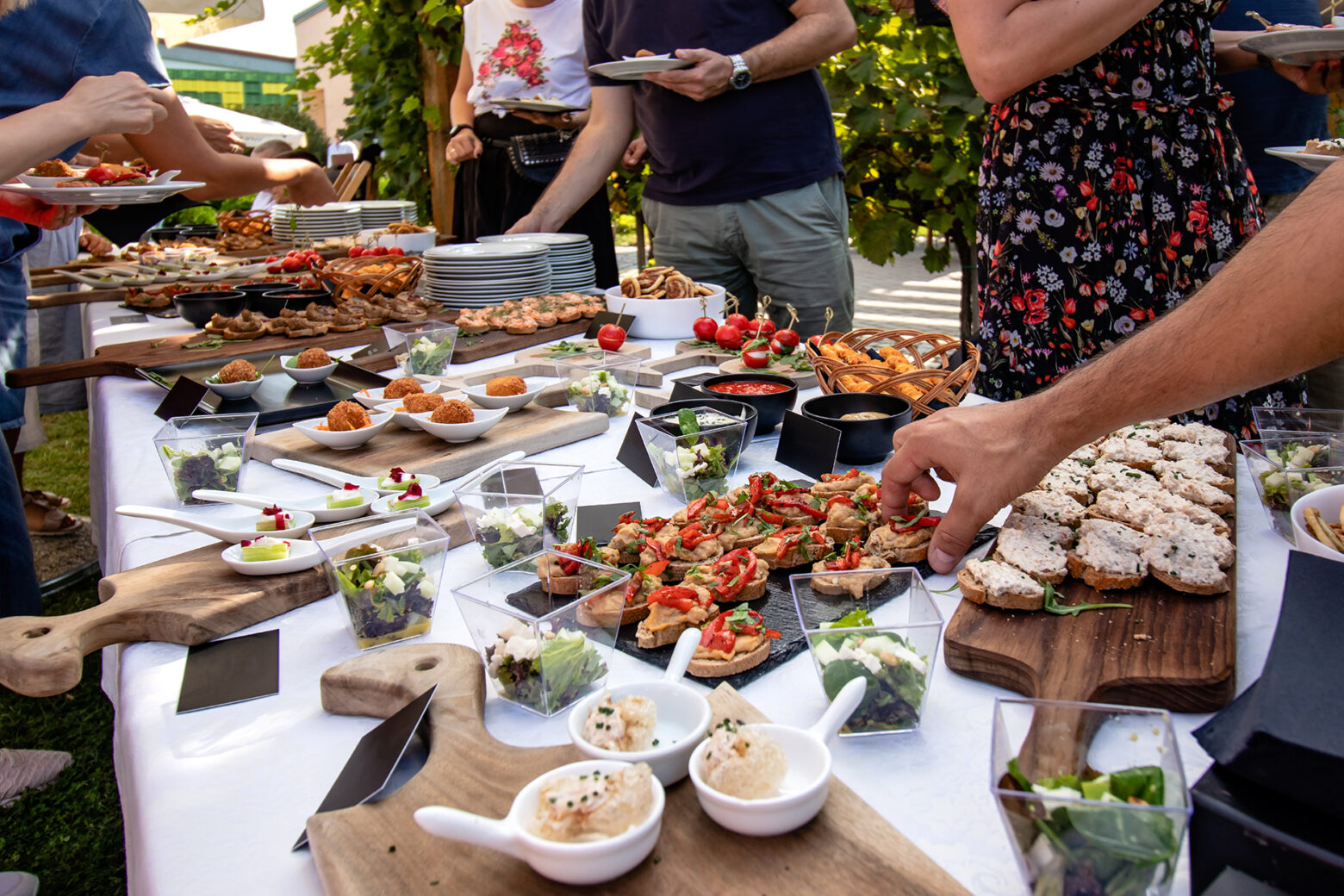 Outdoor garden party with buffet table full of canapes. People s